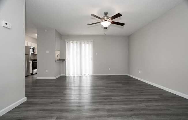 an empty living room with a ceiling fan