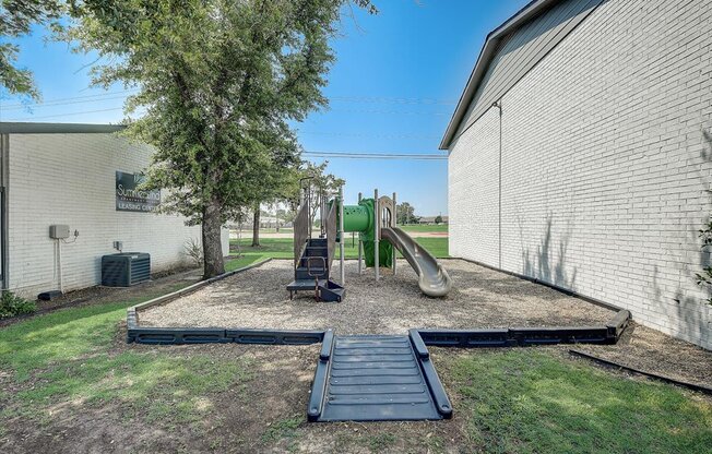 a playground with a slide and a slide in the middle of a grassy area