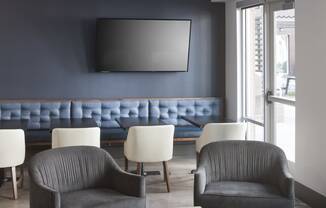 a living room with two gray chairs and a blue couch in the background and a coffee table