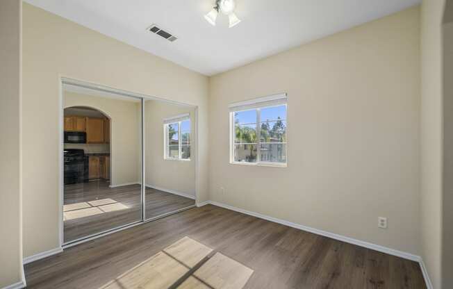 a bedroom with hardwood floors and beige walls at The Village Apartments, California, 91406