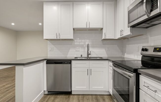 a kitchen with white cabinets and black counter tops