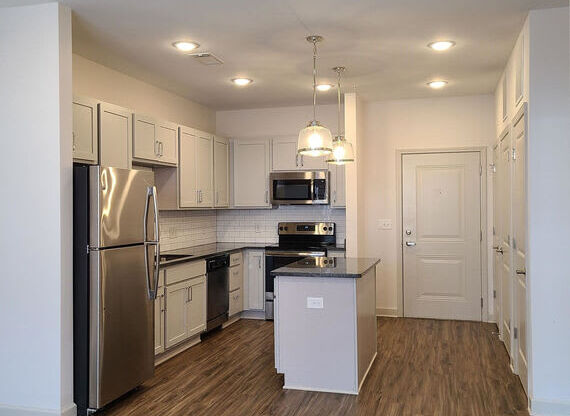 A kitchen with a refrigerator, microwave, oven, and cabinets.