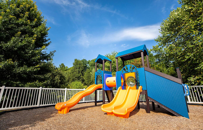 A playground with a blue and orange slide.