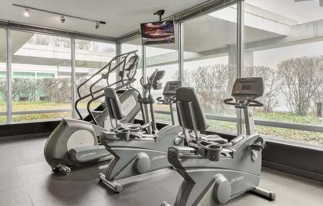 Two exercise bikes are in a room with a window.