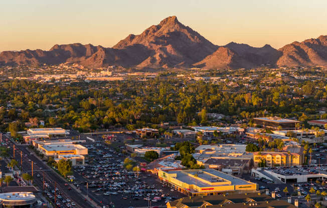 A cityscape with a mountain in the background during sunset.