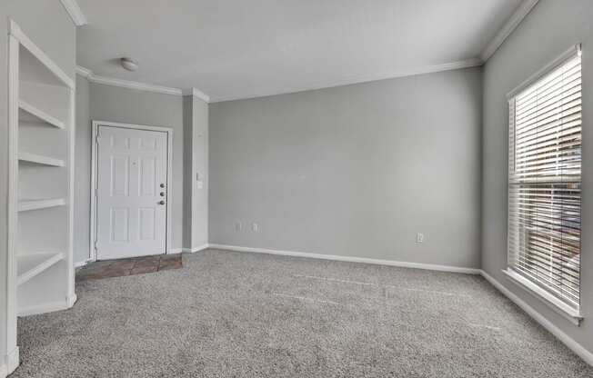 an empty living room with a white door and a window