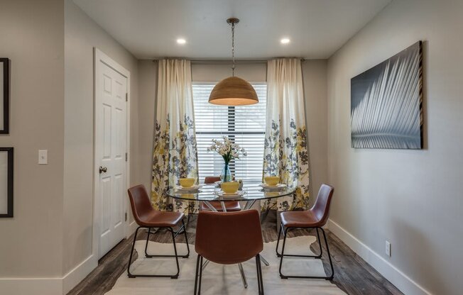 a dining room with a table and chairs in front of a window