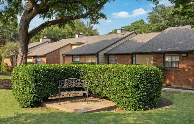 A bench is situated in the middle of a green hedge.