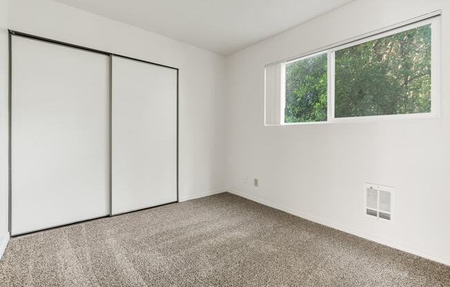 an empty room with carpet and white walls and a window