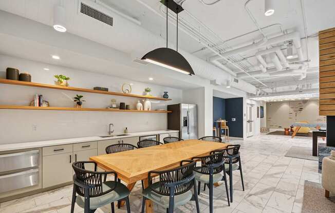 a dining room with a wooden table and black chairs at Link Apartments® Calyx, Chapel Hill