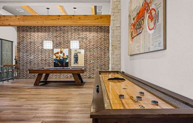 A billiard table is in the middle of a room with a brick wall and a bench.