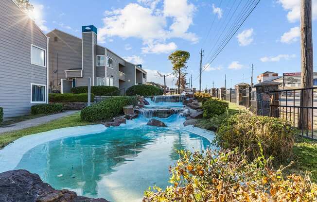 a small pool with waterfalls in front of apartment buildings