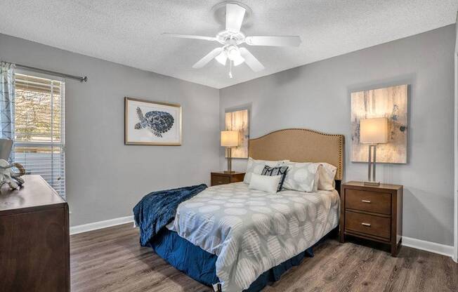 Bedroom with queen sized bed and night stands. Fan on ceiling.