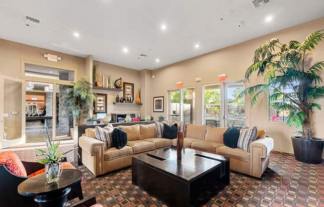 A living room with a couch, coffee table, and potted plants.