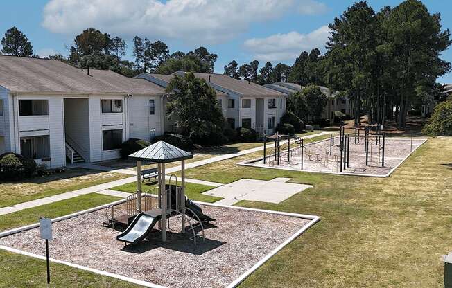 A playground area with a slide and a swing set in the middle of a grassy area.
