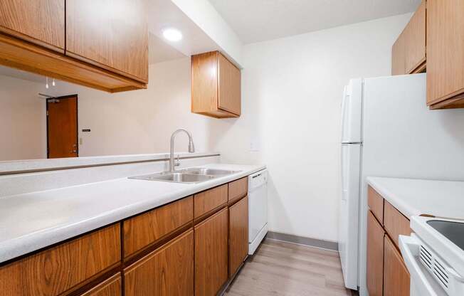 A kitchen with wooden cabinets and a white fridge. at Bristol Ridge, Urbandale, 50322