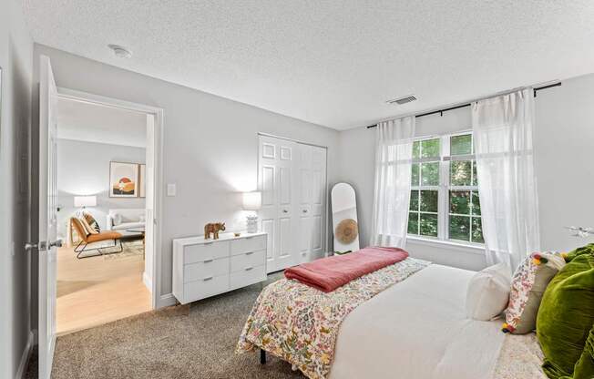 A bedroom with a bed, dresser, and chair.