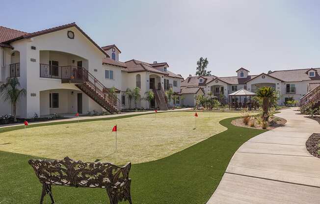 A park area with a bench and a golf hole with a flag.