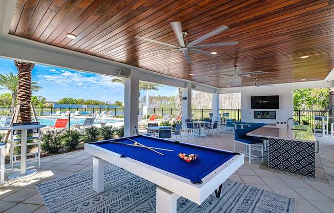a pool table in a covered patio with a view of the pool and the beach at Altis Grand Suncoast, Land O' Lakes, 34638