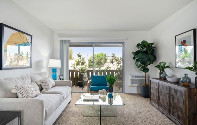 a living room with a white couch and coffee table and a sliding glass door leading to a