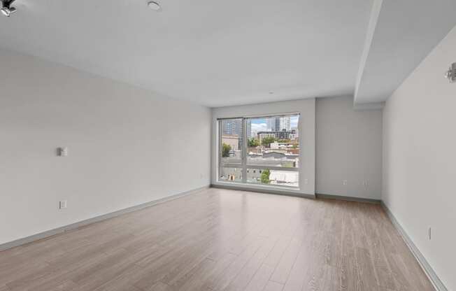 an empty living room with wood floors and a large window