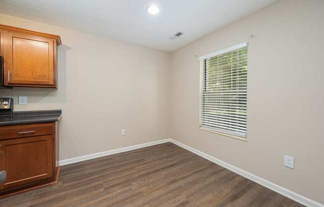 an empty living room with a window and a kitchen