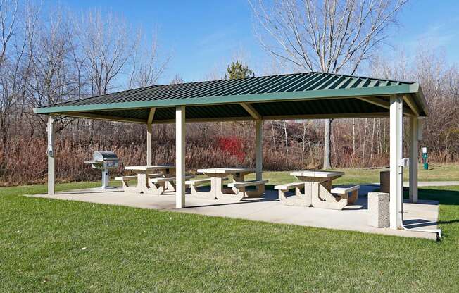 Covered community picnic area with tables and grills for outdoor dining.