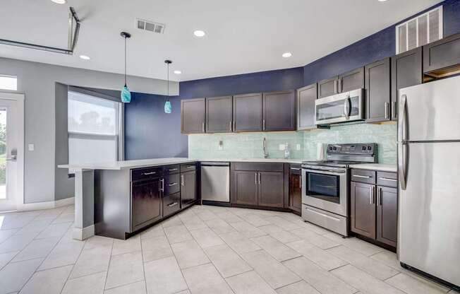 A kitchen with a white refrigerator, stainless steel oven, and black cabinets.