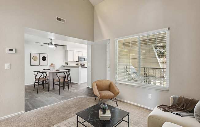 Model Living Room with Carpet and View of Kitchen/Dining Area with Wood-Style Flooring at Broadmoor Village Apartments in Salt Lake City, UT.