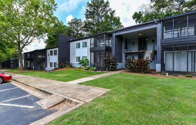 a row of apartment buildings with a grassy yard and trees in the background