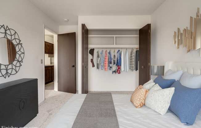 a bedroom with a large bed and a closet with clothes hanging on the wall