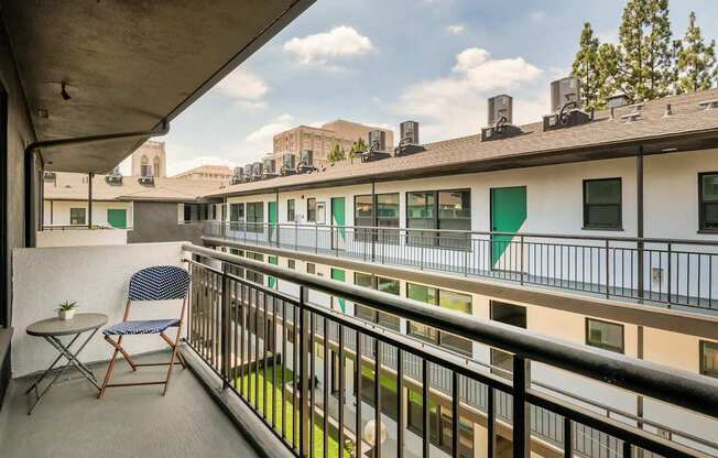 A balcony with a table and chairs overlooks a courtyard.