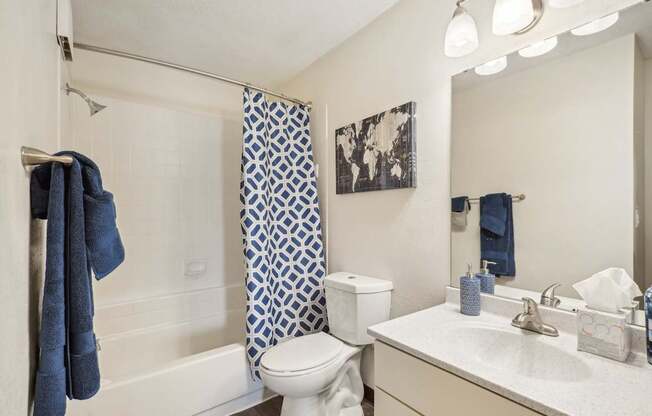 A white bathroom with a blue towel hanging on the shower rod.