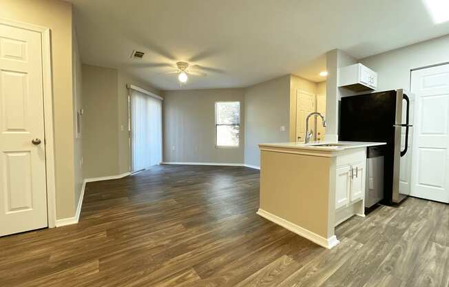 an empty kitchen and living room with a refrigerator and a sink