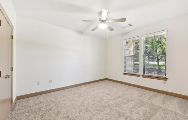 an empty living room with a ceiling fan and a window