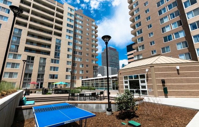 a blue ping pong table is in a courtyard between two tall buildings