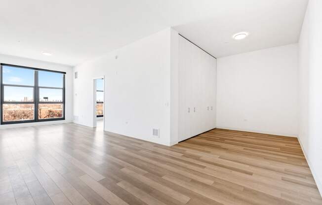 a living room with white walls and wooden floors and a window