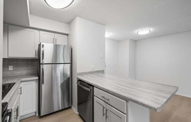 a kitchen with white cabinets and a stainless steel refrigerator