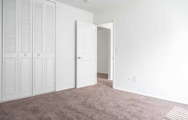 an empty bedroom with white closet doors and carpet