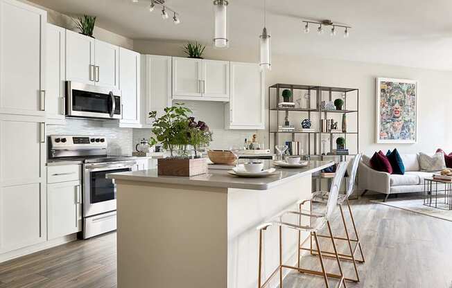 A modern kitchen with white cabinets and a wooden floor.