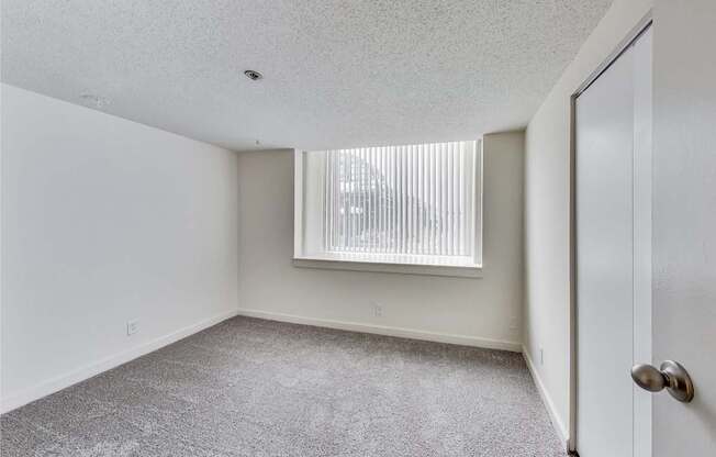 A room with a carpeted floor and a window with blinds at Lowertown Commons Apartments, St. Paul, Minnesota