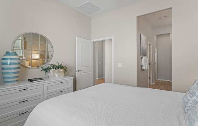 a bedroom with a white bed and a mirror