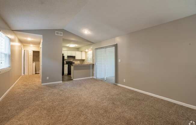 A spacious living room with a kitchen in the background.