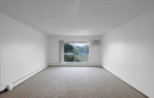 a bedroom with a large window and white walls