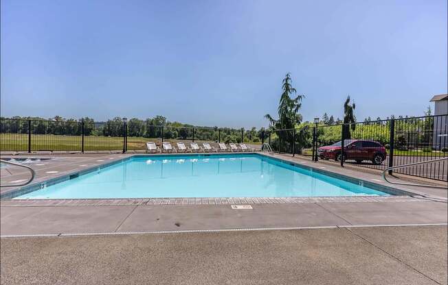 A large outdoor swimming pool surrounded by a fence at Riverplace Apartment Homes, Independence