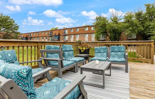 a deck with chairs and a table with a vase of flowers on it