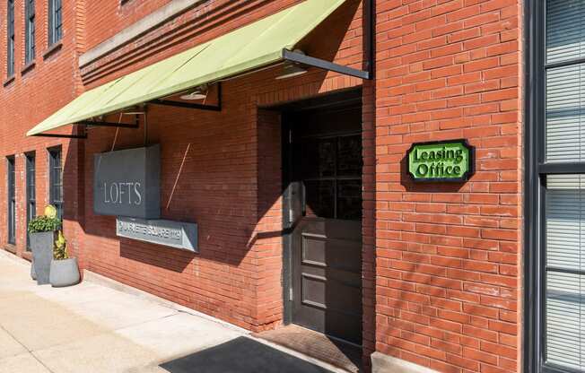 a brick building with a green awning and a door to a tasting room