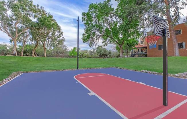 A basketball court with a red and blue surface and a basketball hoop.