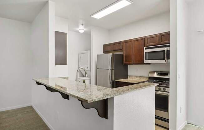 A kitchen with a white counter top and stainless steel appliances.