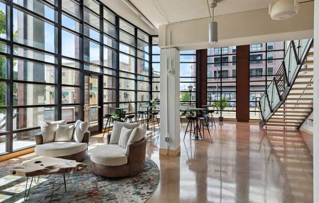 a large living room with floor to ceiling windows and a staircase to the second floor